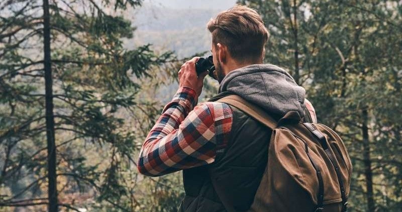 Mann som ser med kikkert ut i horisonten